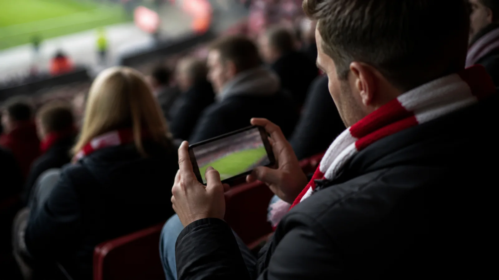 Voksen fan følger en livekamp på en smartphone